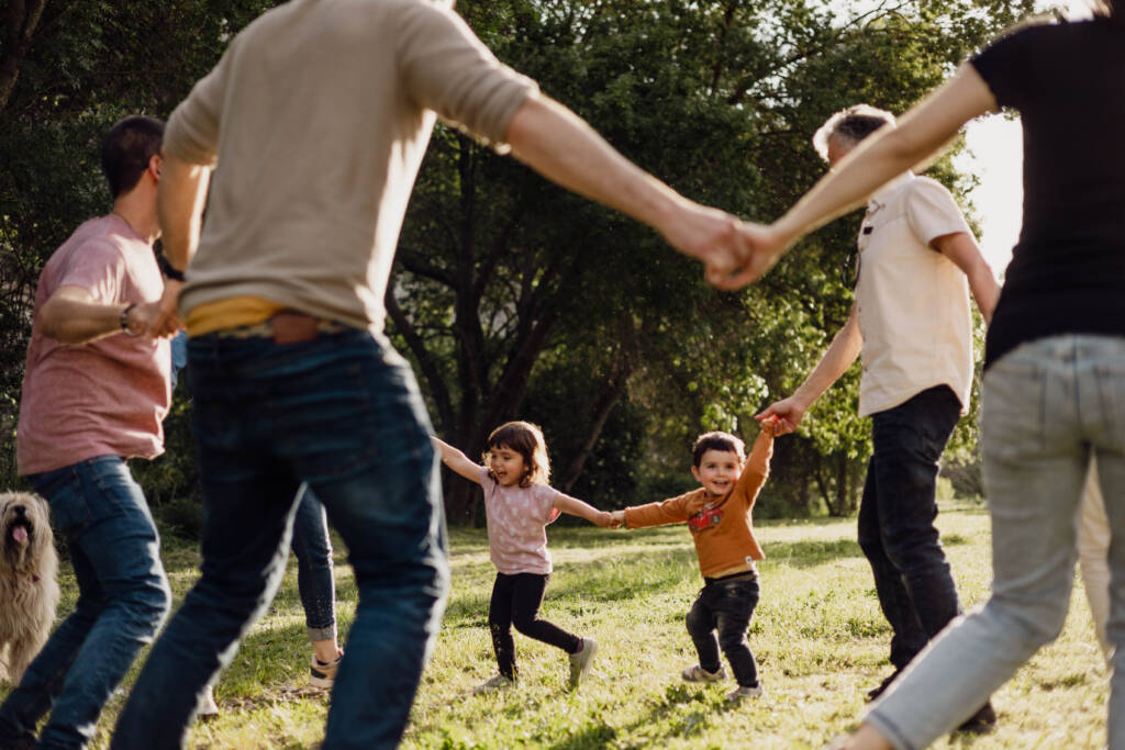 Famílies jugant en cercle en un parc amb nens somrient