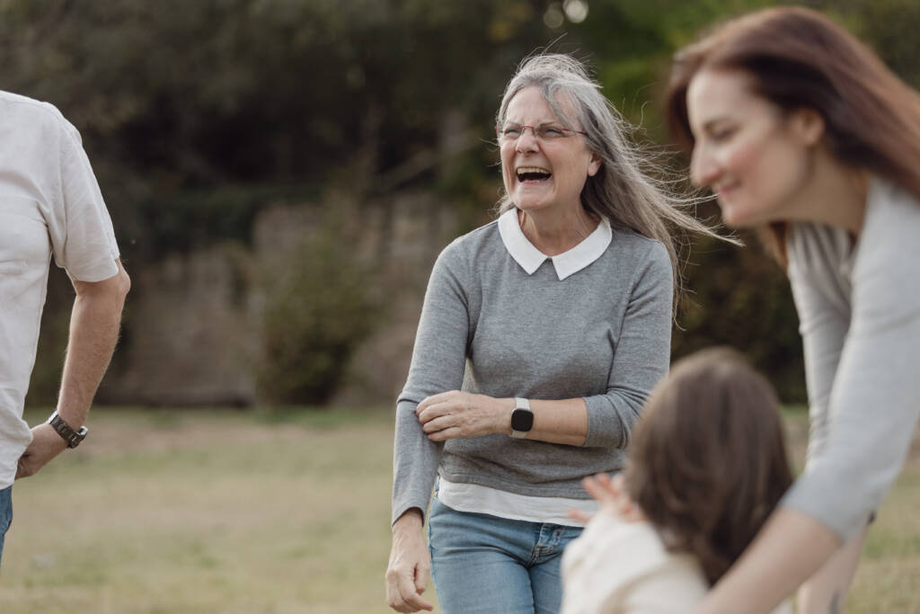 Fotografia de llum natural en família - àvia rient i jugant amb la família