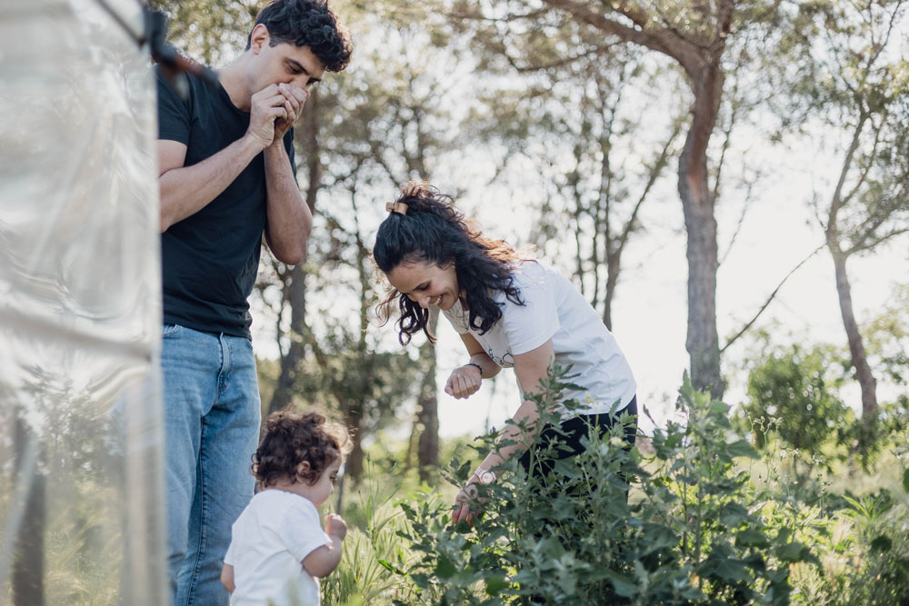 Fotografia de llum natural de família - pares i fill jugant junts a l'exterior