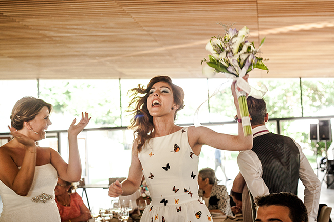 Dona celebrant amb entusiasme amb un ram de flors durant una festa de casament.